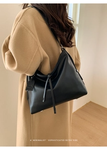 Gros plan d'un sac à bandoulière en cuir noir minimaliste avec long pendentif décoratif