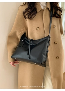 Sac à bandoulière minimaliste en cuir noir au style rétro porté par un mannequin