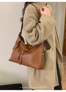 Sac bandoulière chic en cuir marron avec cordon de serrage porté sur un trench-coat
