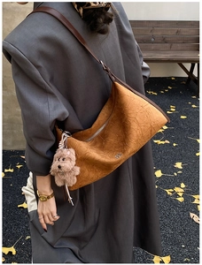 Close-up of mustard yellow leather tote with textured wrinkles and brown poodle charm