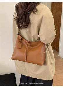 Détail du grand sac cabas en cuir caramel porté avec un trench-coat beige