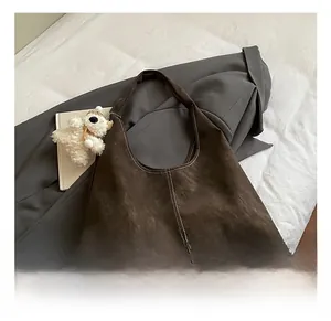 Detailed macro view of the brown suede tote bag featuring contrast stitching and a plush charm