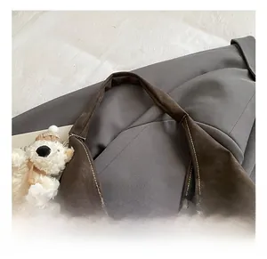 Detail showing high-quality stitching on dark brown leather handle with bear charm