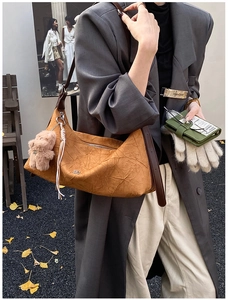 Detail of caramel hobo bag with teddy charm and brown leather strap on model