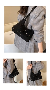 Detailed view of black suede hobo bag with vintage gold rivets and crescent moon shape