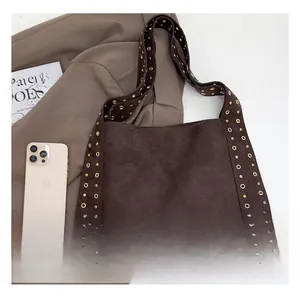 Detail of deep brown suede tote with metal rivets and phone for scale reference