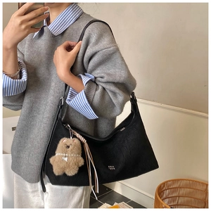 Close-up of black retro hobo shoulder bag with a cute brown plush bear charm