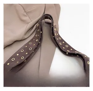 Macro shot of brown suede long shoulder strap with gold grommets and vintage rivets