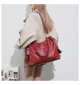 Close-up of red large tote bag with silver zippers and textured leather detail