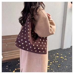 Close-up of retro brown suede tote bag featuring decorative golden metal rivets