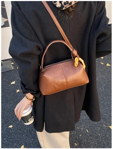Sac à bandoulière en cuir marron Maillard avec boucle dorée sur fond de rue d'automne