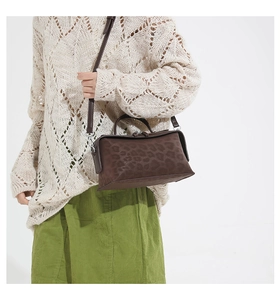 Détail d'un sac bandoulière léopard avec des poignées en cuir et une bandoulière réglable