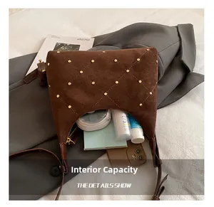 Detailed interior capacity of brown suede shoulder bag with gold studs and zipper