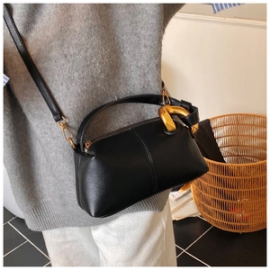 Détail du sac cylindrique noir grainé avec chaîne dorée épaisse et fine bandoulière
