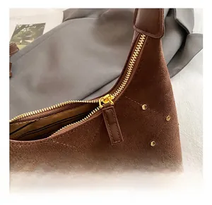 Close-up of golden rivets and metal zipper on brown frosted leather shoulder bag