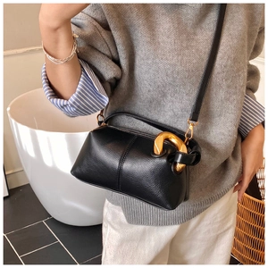 Détails du sac noir en cuir grainé avec poignée métallique dorée et bandoulière amovible