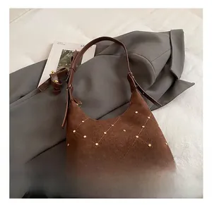 Detailed view of brown suede shoulder bag featuring a unique geometric rivet diamond pattern