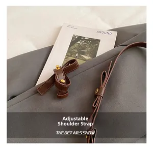 Detail of adjustable dark brown leather shoulder strap with golden metal buckle