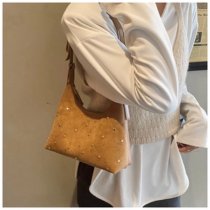 Detail of brown suede hobo bag with diamond quilted stitching and gold rivet accents