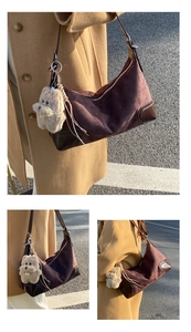 Detail of retro brown suede hobo bag with leather corners and cute plush puppy pendant