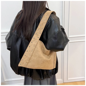 Detail of vintage camel suede shoulder bag with industrial metal rivets on wide strap