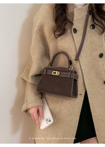 Close-up of retro dark brown suede crossbody bag with elegant gold oval twist lock
