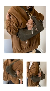 Detail of olive green suede shoulder bag with cute brown teddy bear plush charm