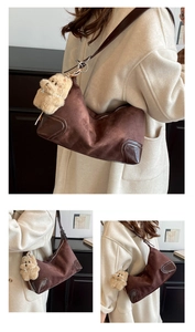 Detail of brown suede dumpling bag with leather trim and plush bear charm accent