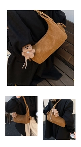Detail view of brown suede half-moon bag featuring a plush bear charm and adjustable strap