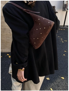 Close-up of brown suede hobo bag with gold rivet diamond pattern on black coat