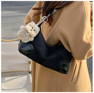 Detail of black half-moon bag in mixed leather texture with a cute puppy bag charm