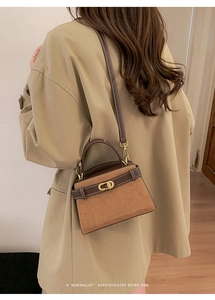 Detail of a brown matte retro handbag with gold clasp and elegant contrast stitching