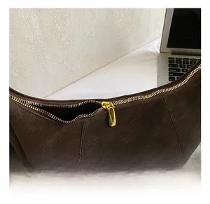 Detail of premium gold-tone zipper and textured brown leather on a hobo shoulder bag