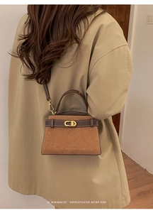Detail of vintage brown suede crossbody bag featuring gold CD lock and white stitching