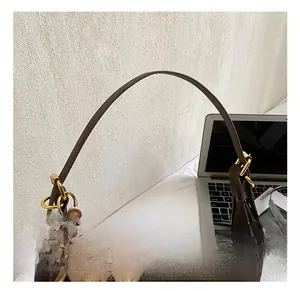 Detail of dark brown suede crescent bag featuring golden hardware and a cute plush bear charm