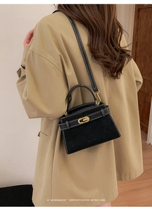 Detail of vintage suede handbag featuring white stitching and gold turn-lock closure