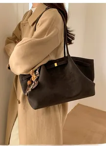Detail of dark brown suede tote bag featuring a golden buckle and leopard tassel charm