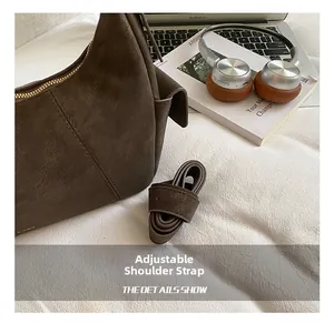 Detail of deep brown frosted suede crossbody bag with adjustable strap and metal zipper