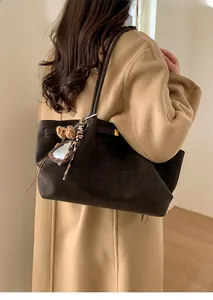 Close-up of a dark brown suede tote bag featuring a leopard print plush charm detail