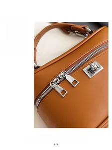 Detail of caramel leather handbag featuring dual smooth silver zippers and top handle