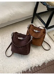 Detail of suede bucket bags featuring woven handles and silver metallic twist locks