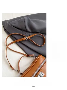 Close-up of brown pebbled leather handbag featuring silver zippers and adjustable strap