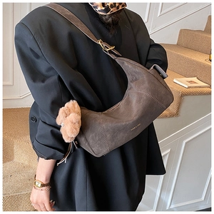 Detail view of a matte brown crescent hobo bag with gold hardware and logo on leather
