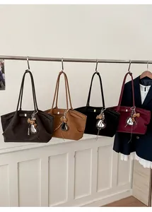 Detailed view of four colors of large tote bags with decorative charms hanging on a rack