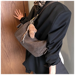 Close-up of vintage brown faux suede shoulder bag with plush bear charm and gold hardware