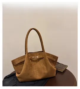 Detail of brown suede tote bag featuring a metallic buckle and decorative strap