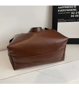 Detail showing the reinforced stitching and soft leather texture of a dark brown tote bag