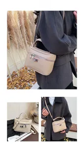 Detail view of beige vanity box bag in faux leather with gold lock and adjustable strap
