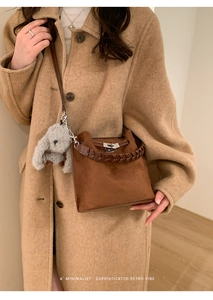 Brown suede bucket bag detail with metal twist lock and cute bunny charm on shoulder strap