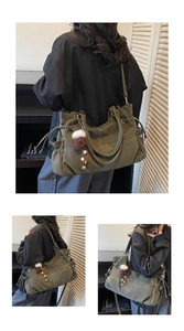 Detail of olive green slouchy tote bag with white stitching and decorative brown pompom